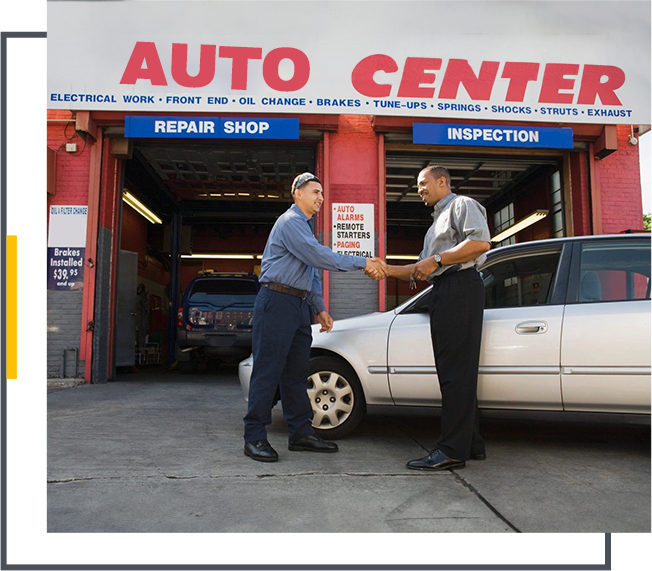 Two men shaking hands in front of a car.